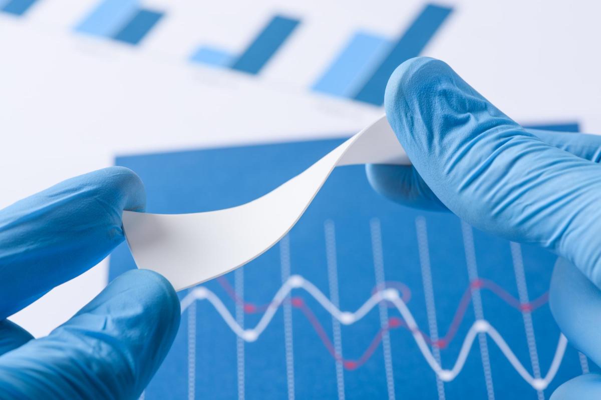 Gloved hands holding novel flexible polmyer material